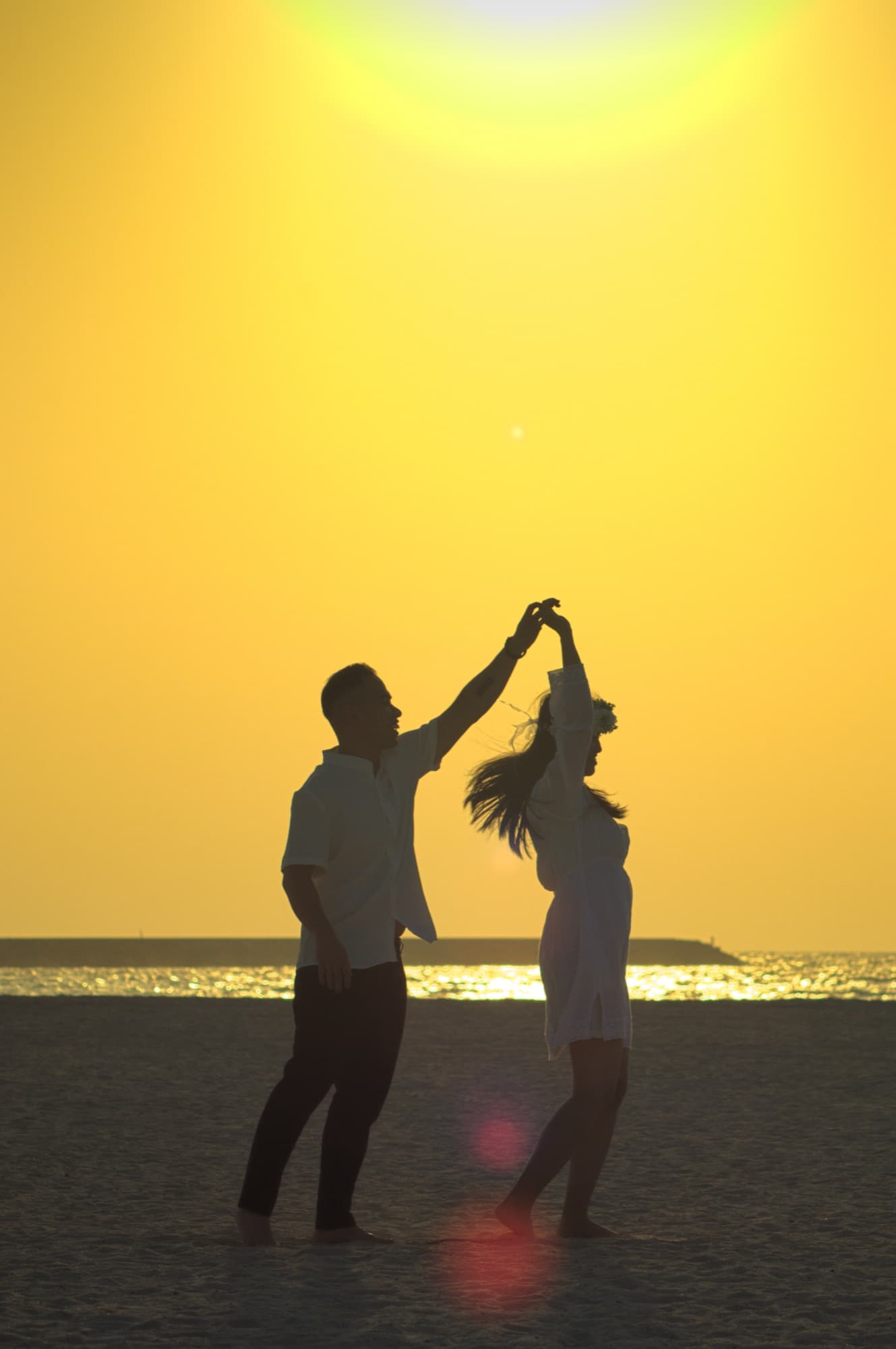 Couple dancing in silhouette against a sunset