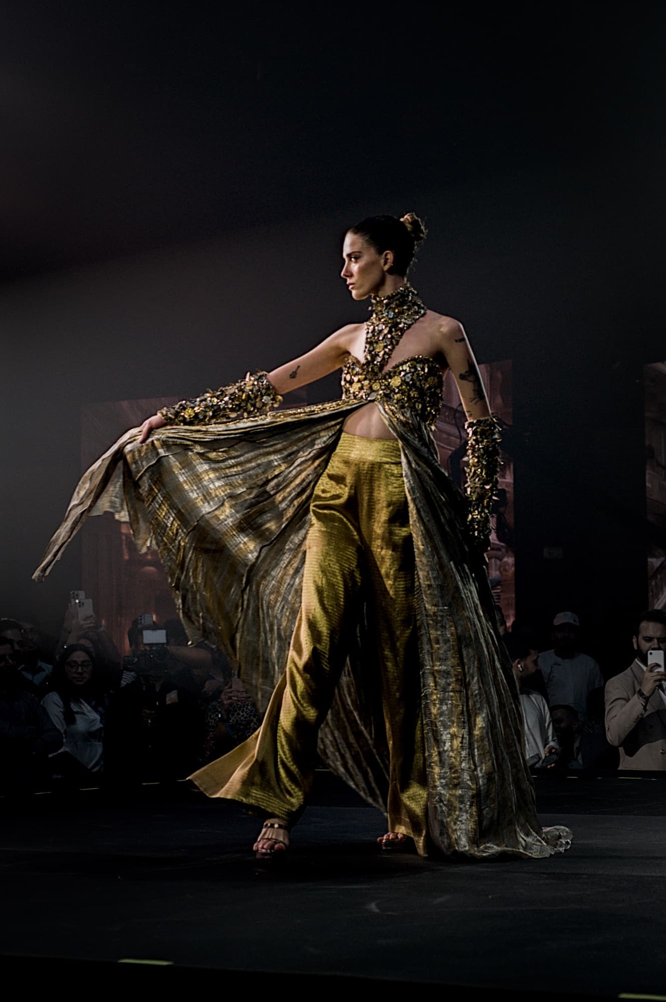 Model in a gold cape on the Elle Residence runway