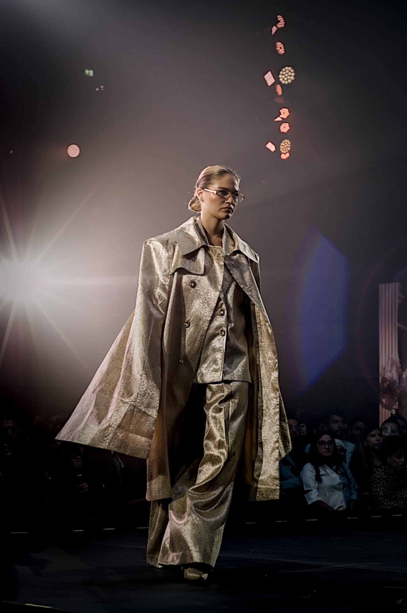 Model in a metallic coat walking the Elle Residence runway