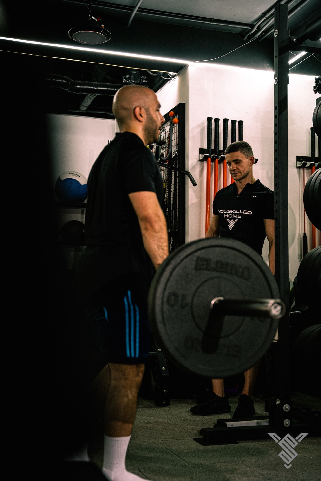 Coach and client beside a loaded barbell at Youskilled