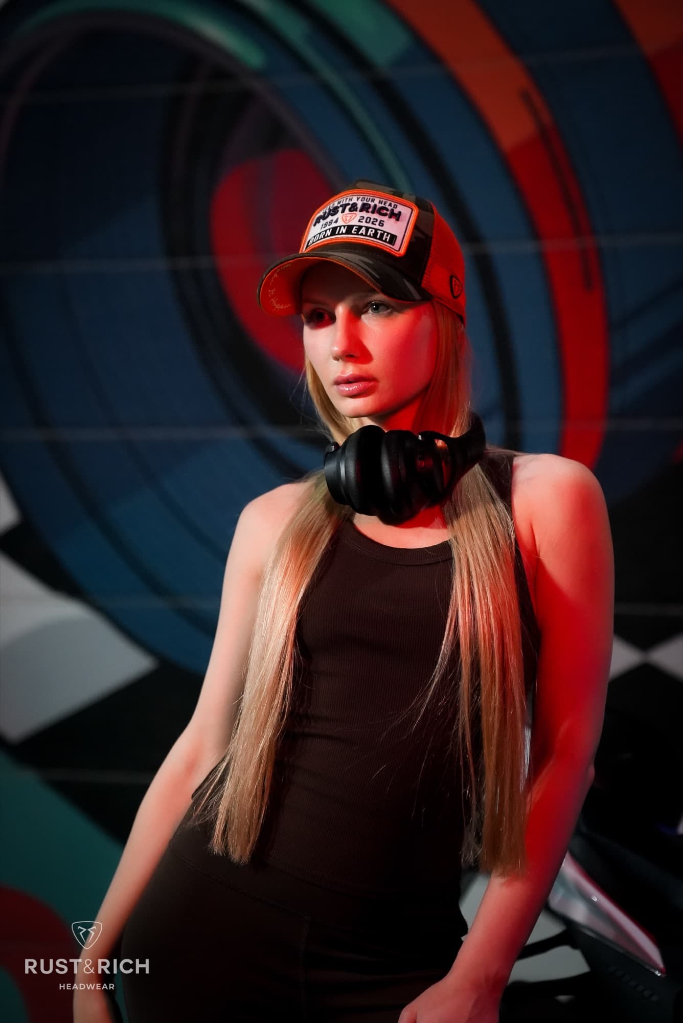 Model in a branded cap and headphones against a graphic backdrop
