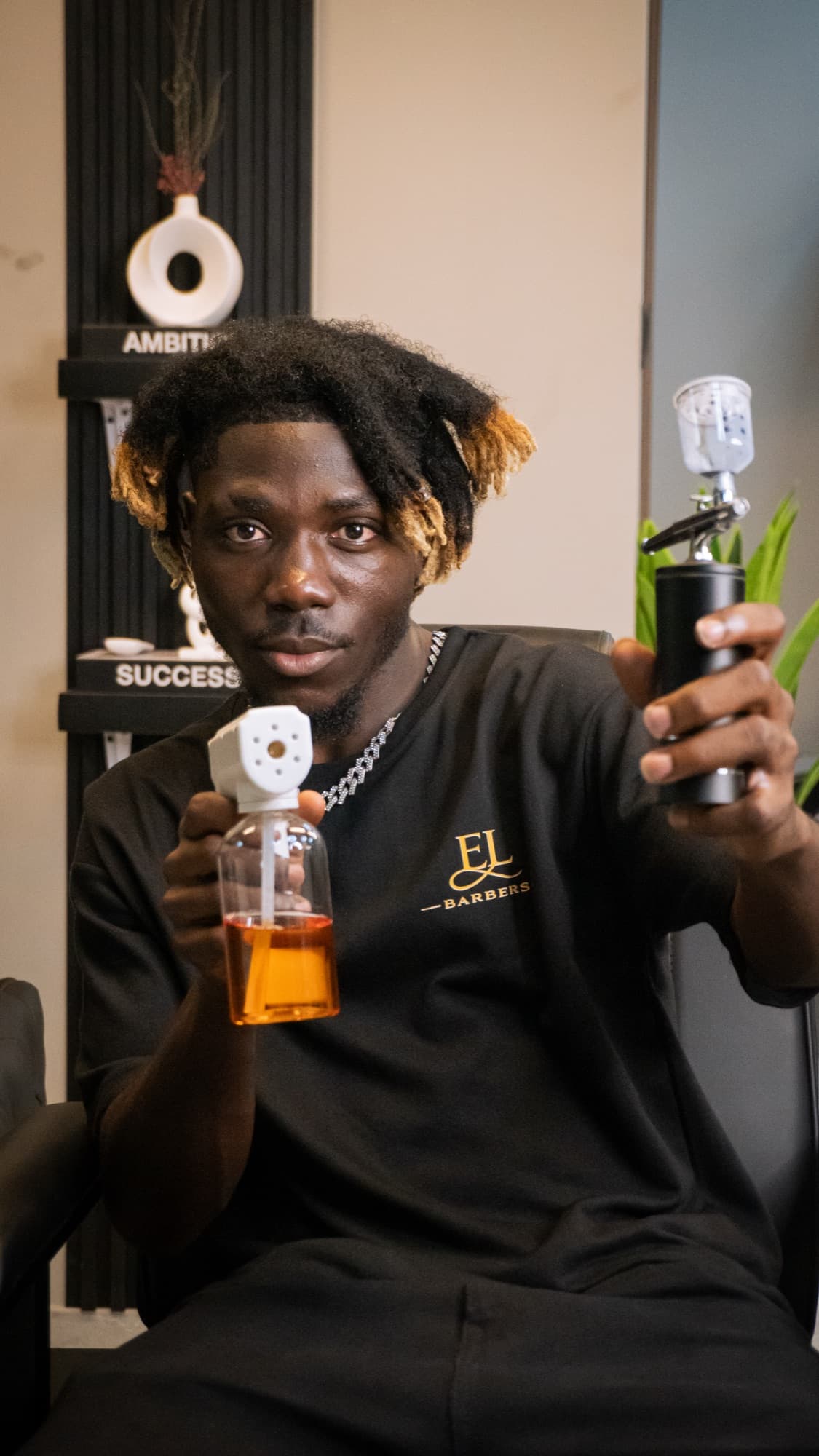 Barber holding up a grooming product at Epic Luxe