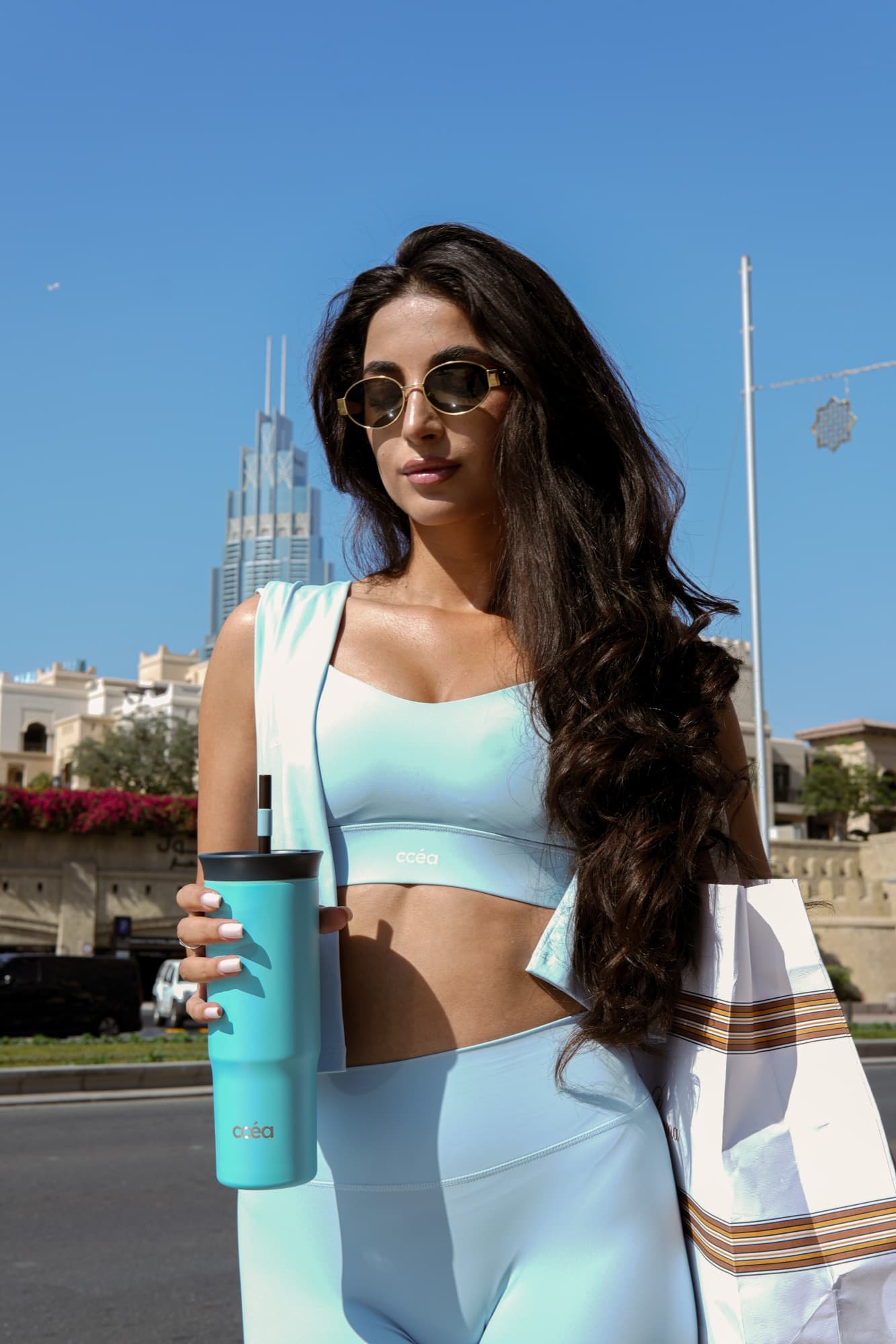 Model holding a CCEA tumbler with the Dubai skyline behind